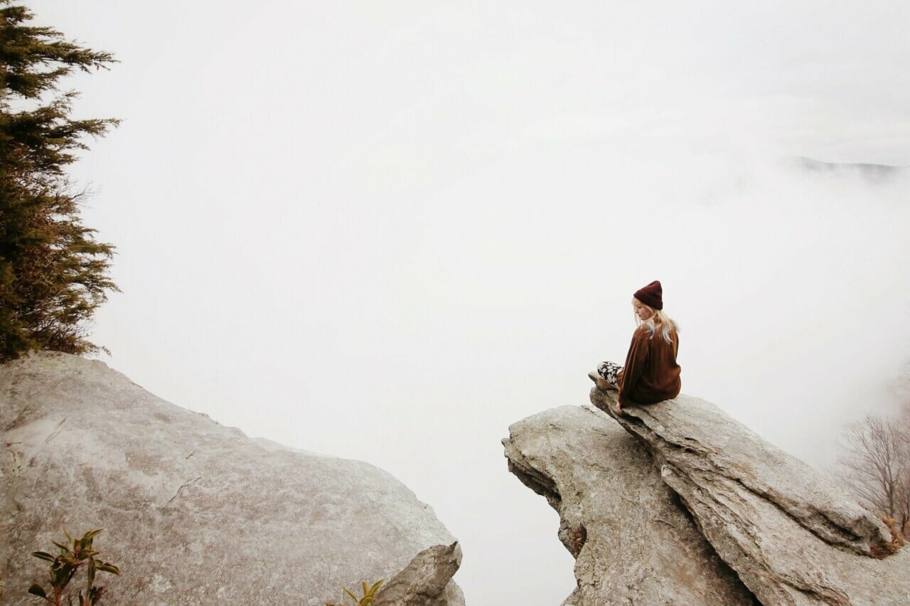 Frau sitzt auf braunem Felsen
